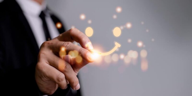 Close-up of a businessman in a suit drawing a glowing smile with his finger, symbolizing innovation and positive outcomes.